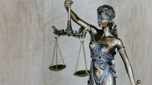 Estátua da Justiça com balança, ilustrando a igualdade entre acusação e defesa.